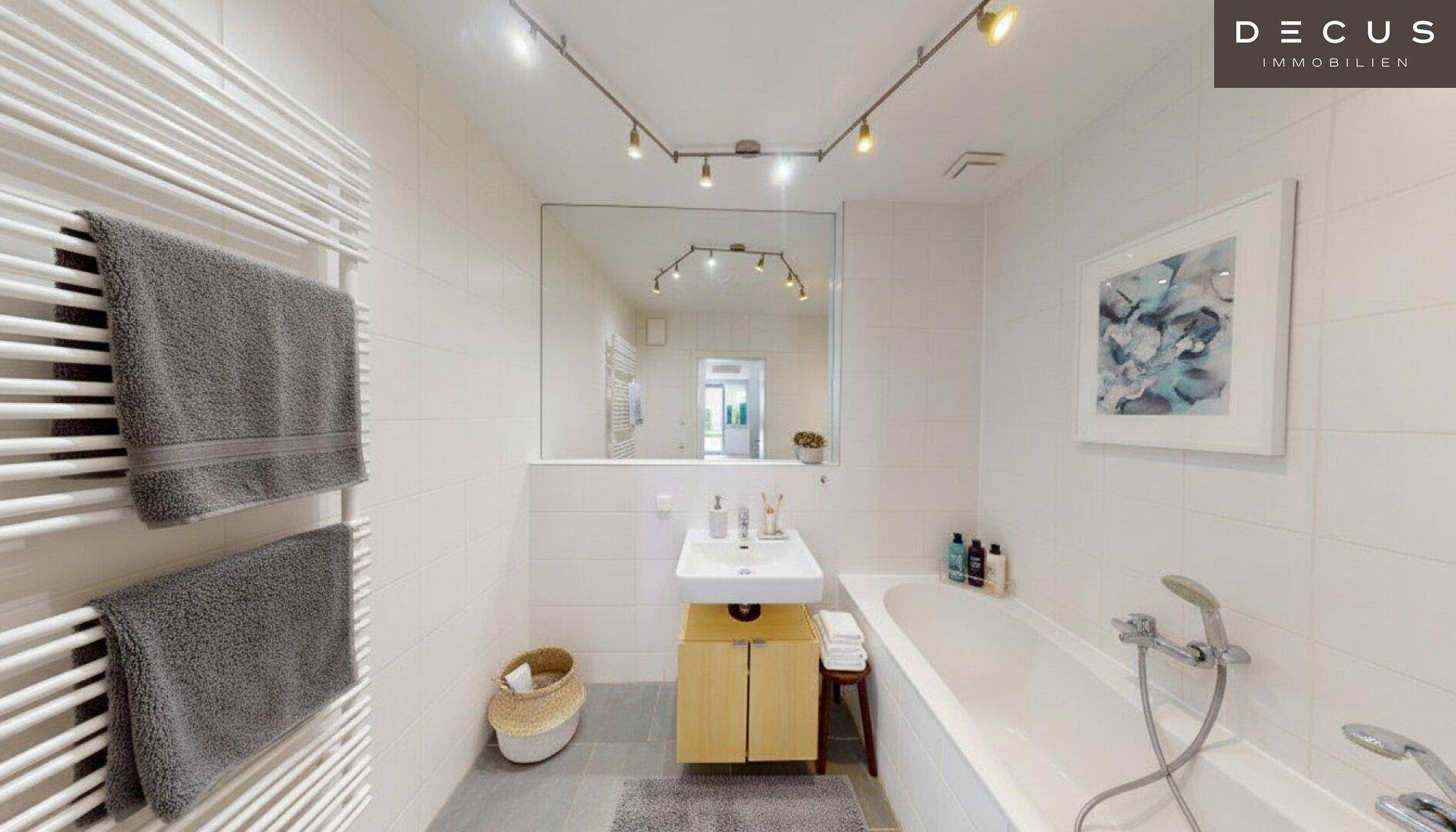 Helles Badezimmer mit Badewanne, Einzelwaschbecken und beheiztem Handtuchhalter.