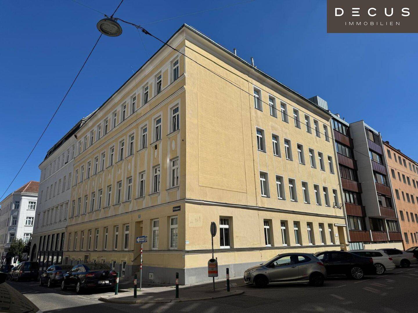 Gelb gestrichenes Eckgebäude mit klassischer Architektur und vielen Fenstern an einer städtischen Kreuzung.