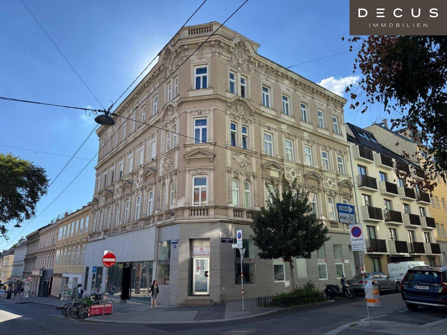 Elegantes Eckgebäude mit klassischer Fassade und Geschäften im Erdgeschoss an einer belebten städtischen Straße.