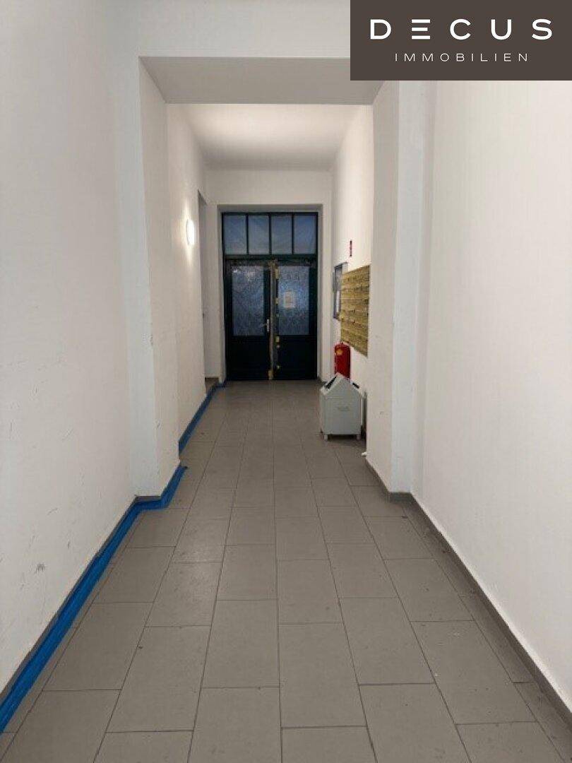 Heller Eingangsbereich eines Mehrfamilienhauses mit Fliesenboden und Zugang zu den Wohnungen.