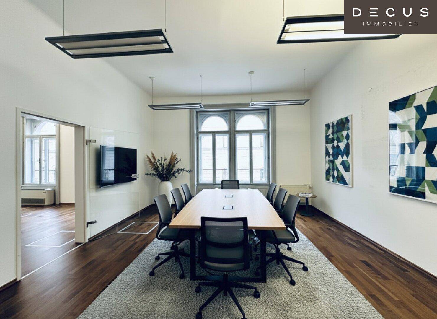 Großer Konferenzraum mit langem Holztisch, bequemen Stühlen und modernen Kunstwerken.