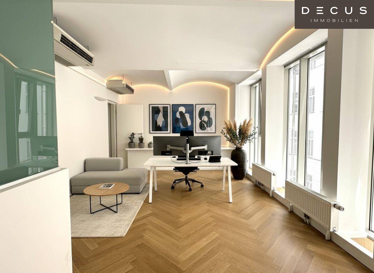 Modern eingerichtetes Büro mit Schreibtisch, Sofa und Kunstwerken an der Wand, ideal für kreatives Arbeiten.