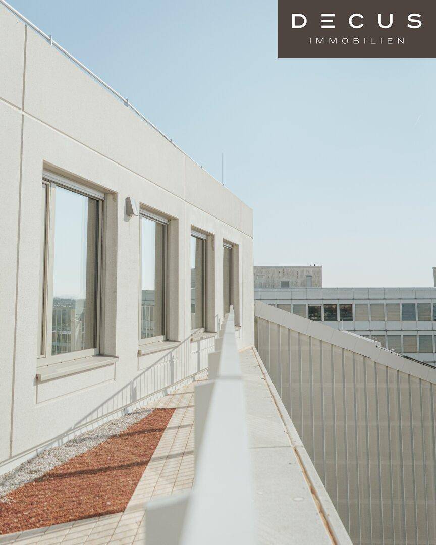 Dachterrasse mit Kiesbelag und Blick auf die umliegende Stadtlandschaft unter blauem Himmel.
