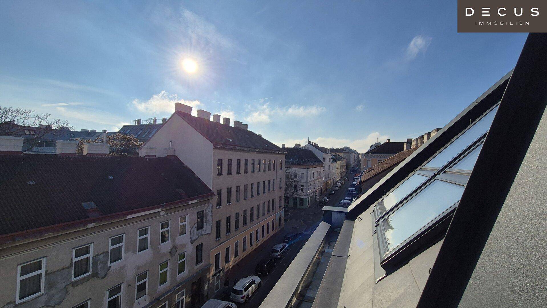 Panoramablick über die Dächer der Stadt an einem sonnigen Tag, mit Blick auf eine belebte Straße.