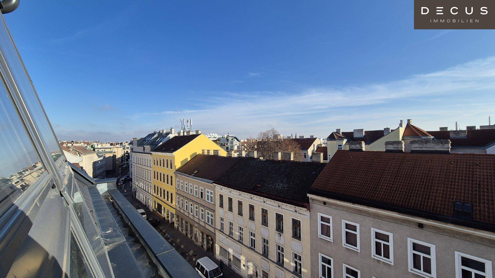 Weitläufiger Blick über die städtische Bebauung und Dächer unter einem klaren blauen Himmel.