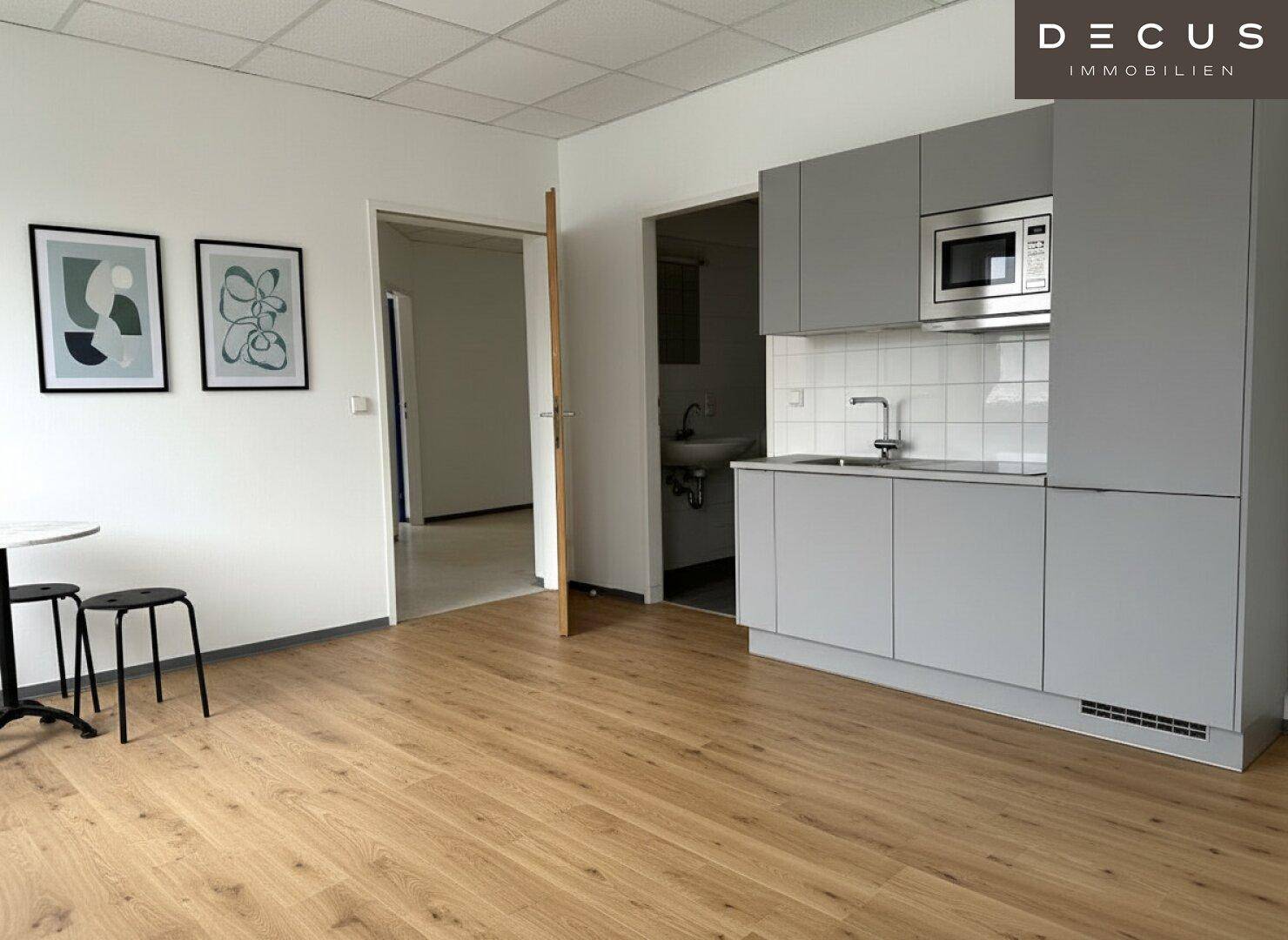 Moderne Küchenzeile mit Mikrowelle und Holzboden, ideal für Pausenbereiche.