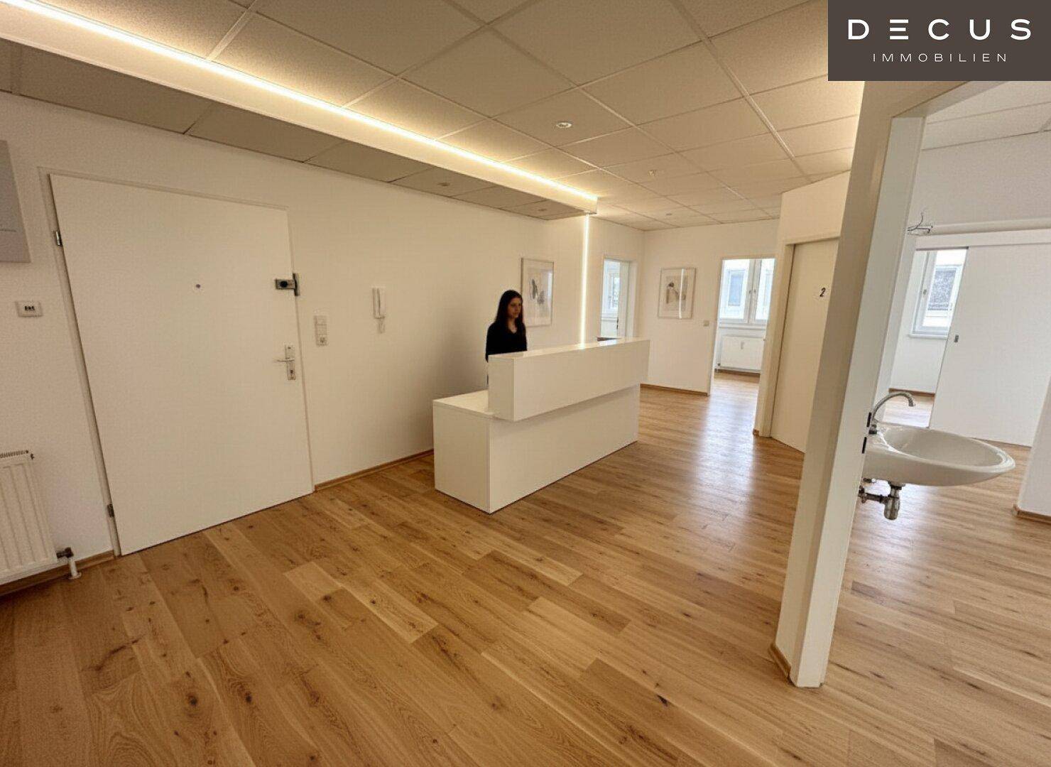 Empfangsbereich mit Holzboden, moderner Theke und Zugang zu weiteren Räumen.