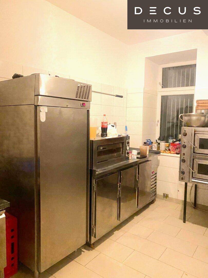 Professionelle Küche mit großen Edelstahlgeräten und Fliesenboden, bereit für den Betrieb.