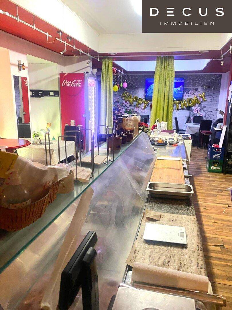 Thekenbereich mit Glasvitrine und Vorbereitungsfläche in einem belebten Gastronomiebetrieb.