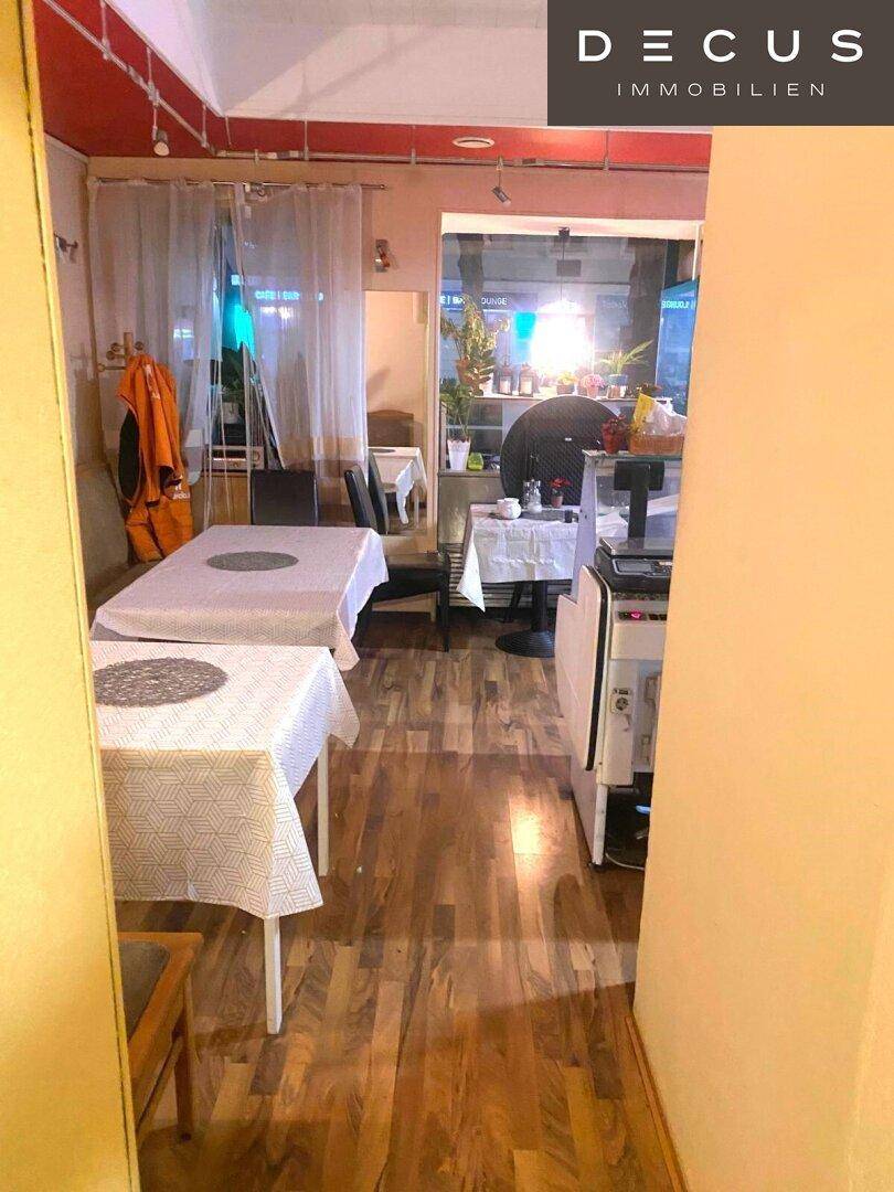 Innenansicht eines Gastraums mit Holzboden und eingedeckten Tischen, bereit für Besucher.
