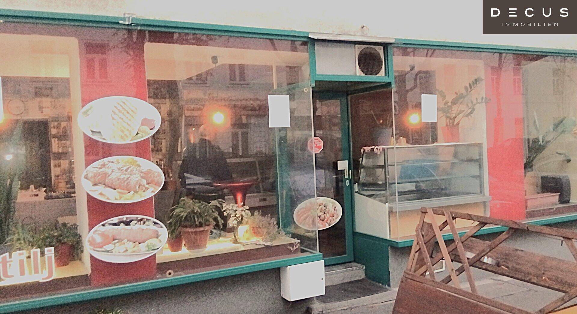 Geschäftsfassade mit großen Schaufenstern, die appetitliche Speisen und Getränke präsentieren.