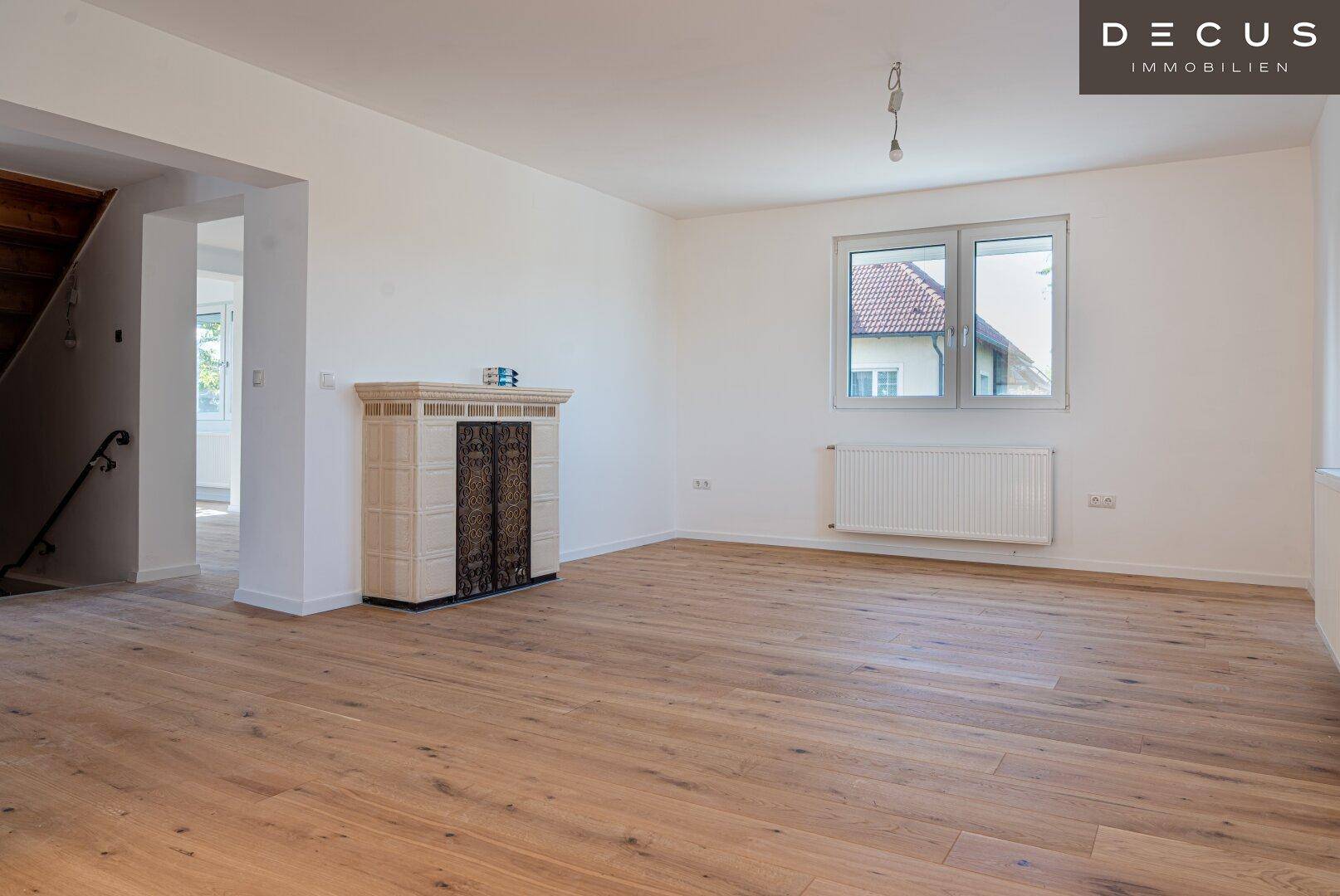 Gemütlicher Wohnbereich mit Holzboden und einem traditionellen Kachelofen als Wärmequelle.