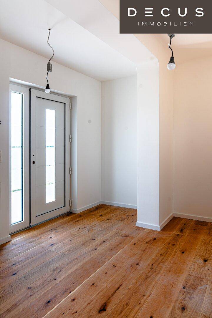 Heller Eingangsbereich mit Holzboden und moderner Haustür, die viel Licht hereinlässt.