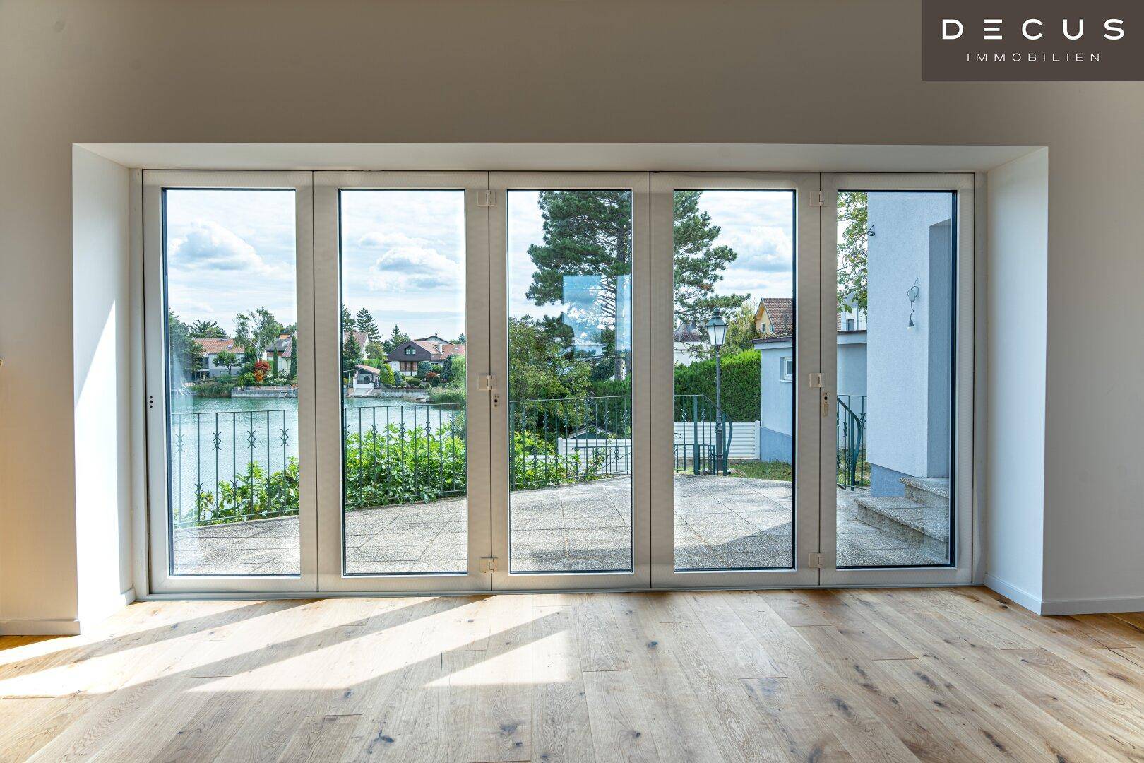Große Fensterfront mit Seeblick und Zugang zur Terrasse, die viel Licht spendet.