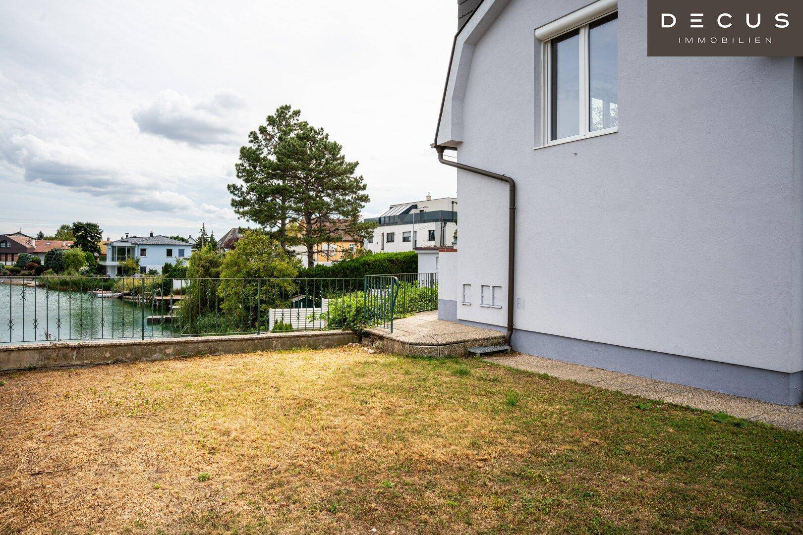 Kleine Rasenfläche neben dem Haus mit Blick auf den See und umliegende Häuser.