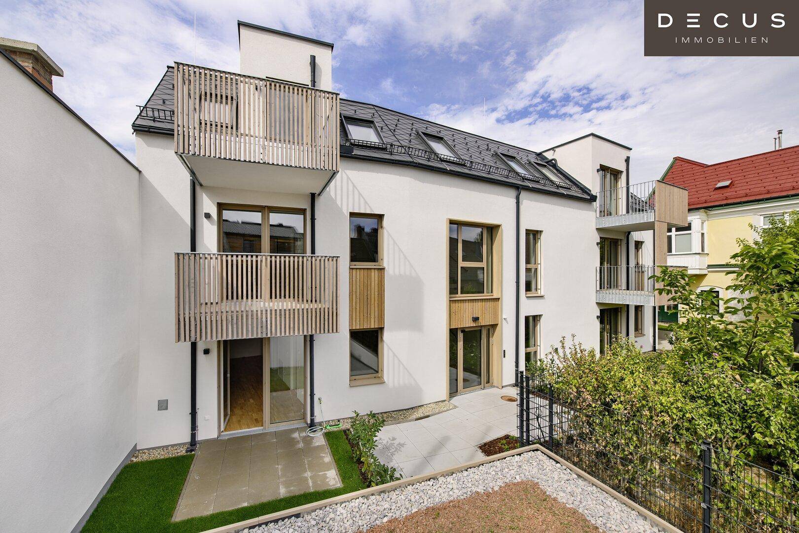 Moderne Wohnanlage mit weißer Fassade, Holzdetails und Balkonen unter bewölktem Himmel.