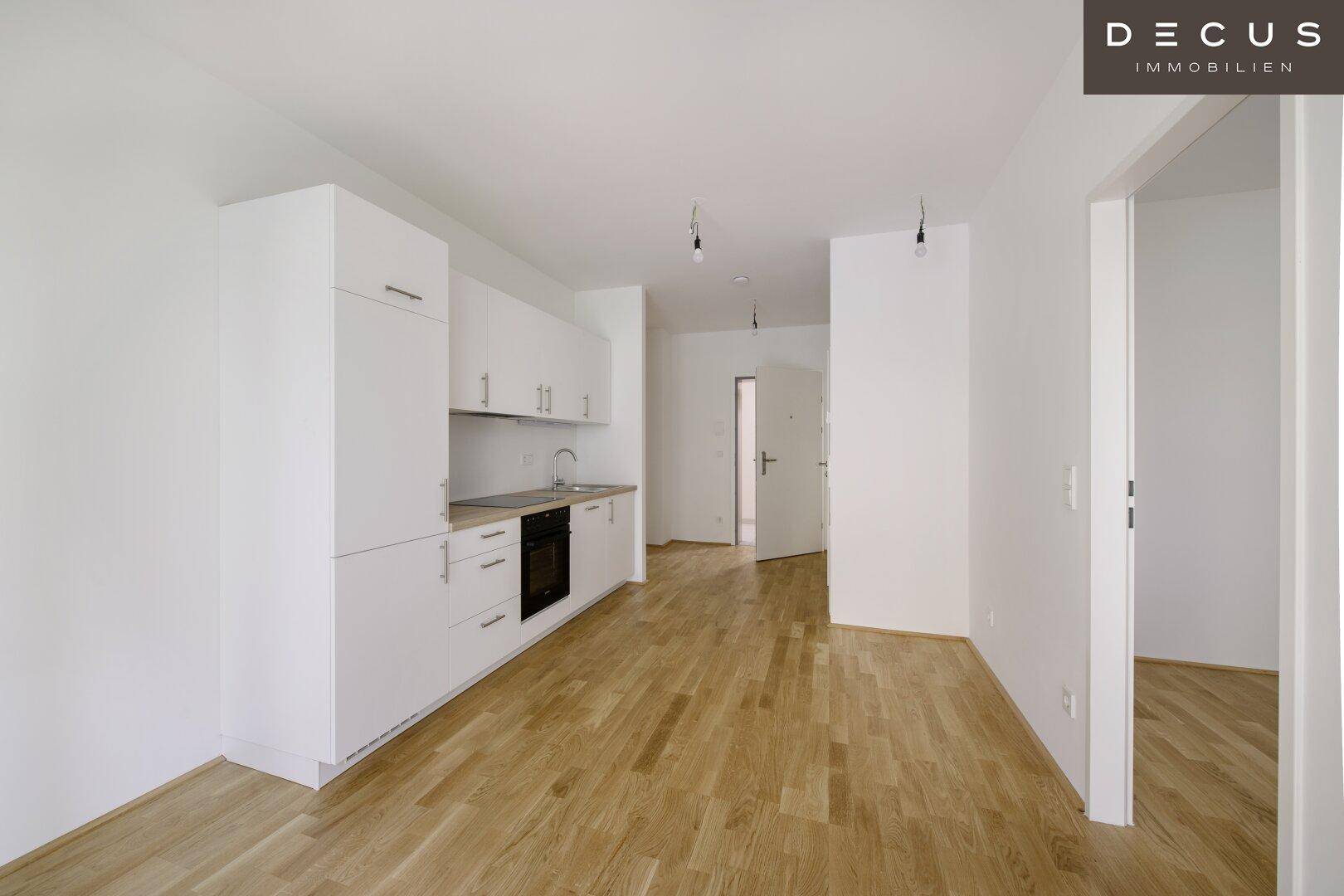 Offener Wohnbereich mit integrierter Küche, Holzboden und viel Tageslicht.