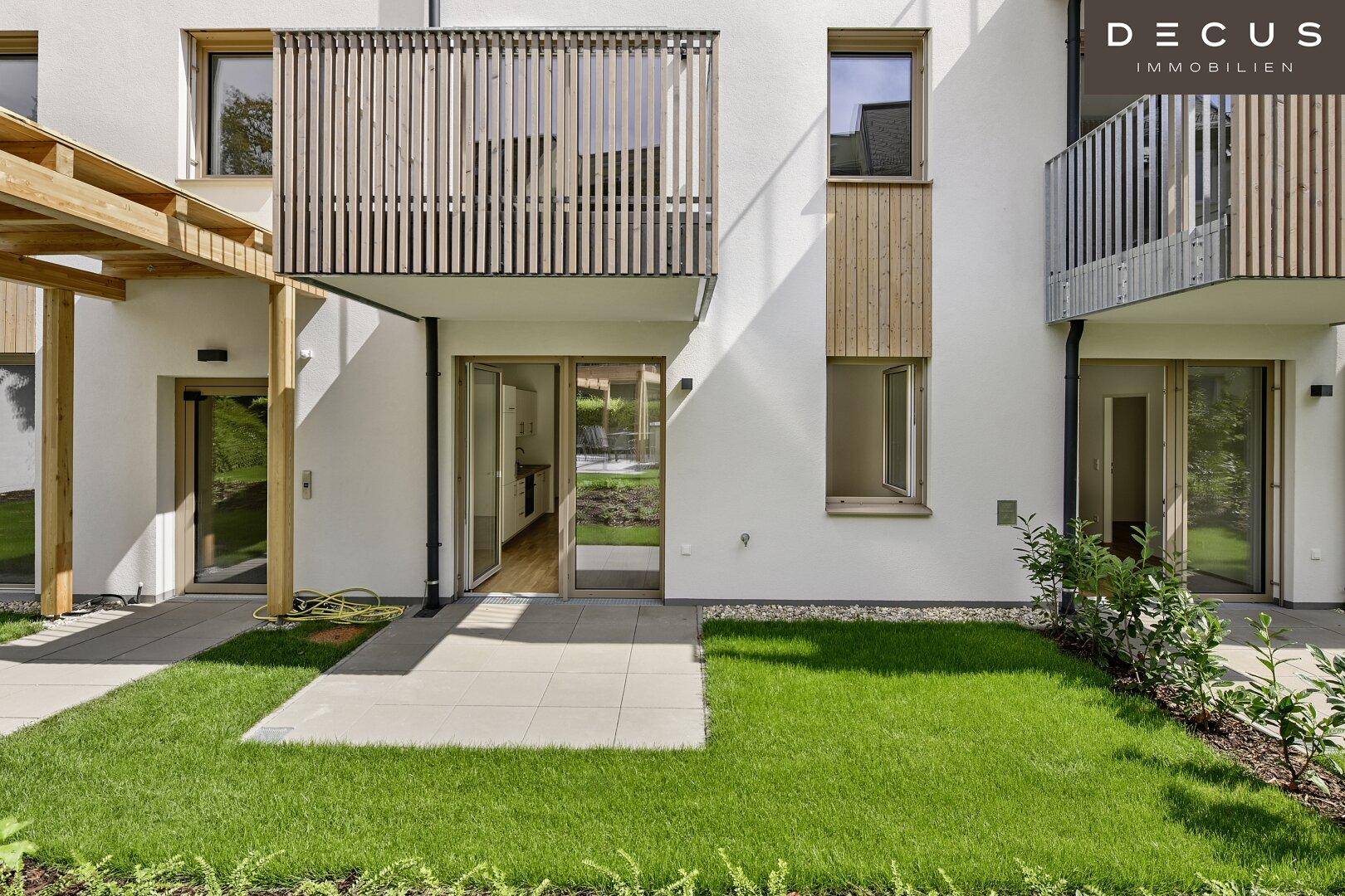 Erdgeschoss-Terrasse mit direktem Zugang zum gepflegten Rasen und Blick auf die moderne Fassade.