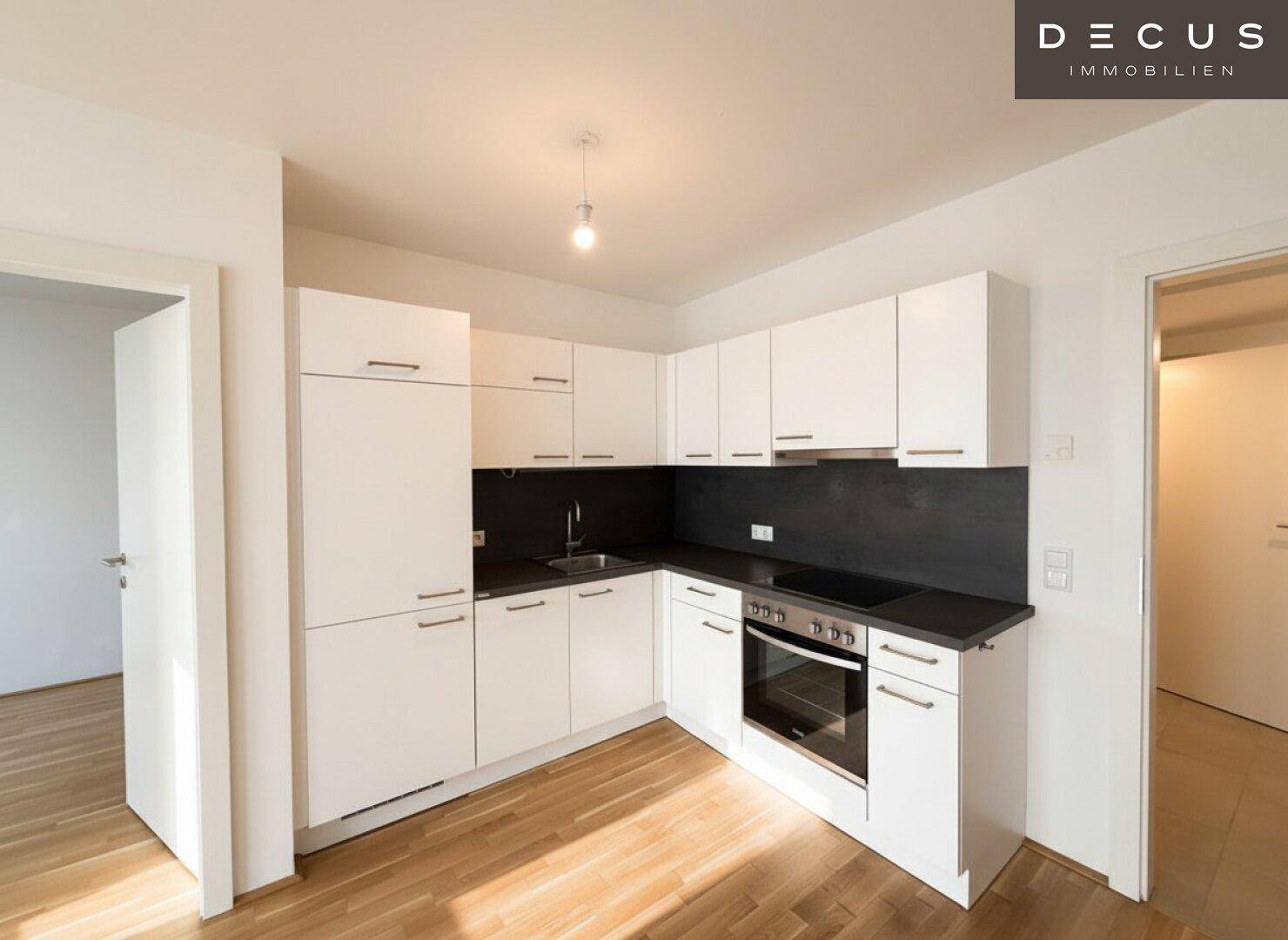 Moderne Einbauküche mit weißen Schränken, dunkler Arbeitsplatte und integrierten Geräten.