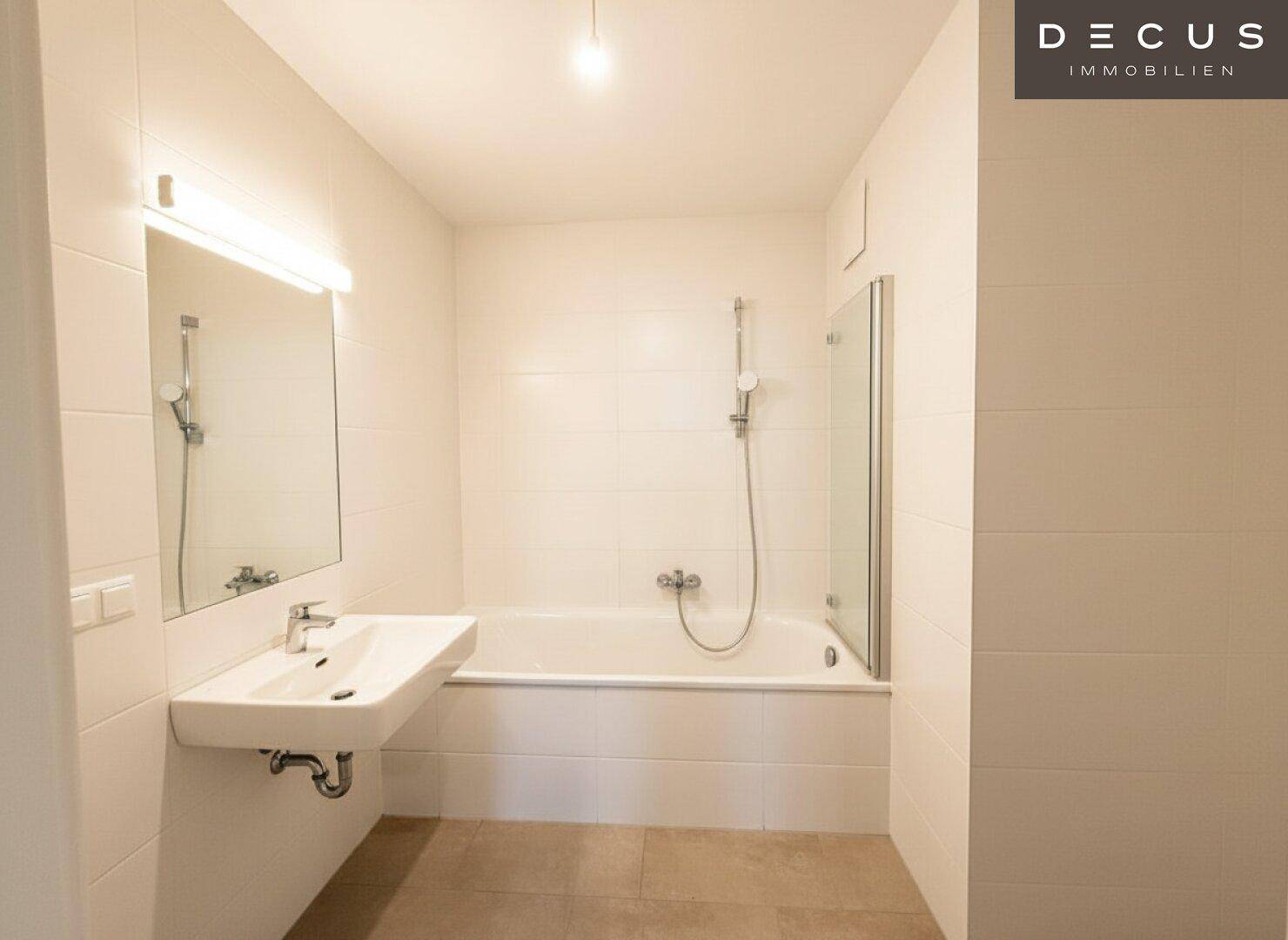 Modernes Badezimmer mit Badewanne, Duschabtrennung und hellem Fliesenboden.