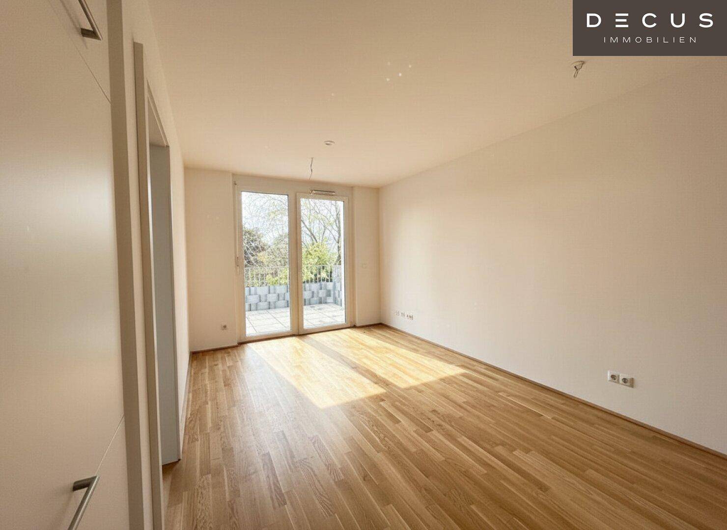 Lichtdurchflutetes Zimmer mit Parkettboden und direktem Zugang zu einem sonnigen Balkon.