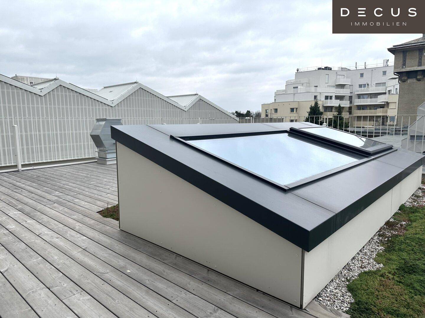 Dachterrasse mit Holzboden, Gründach und modernen Dachfenstern, die viel Licht ins Innere lassen.