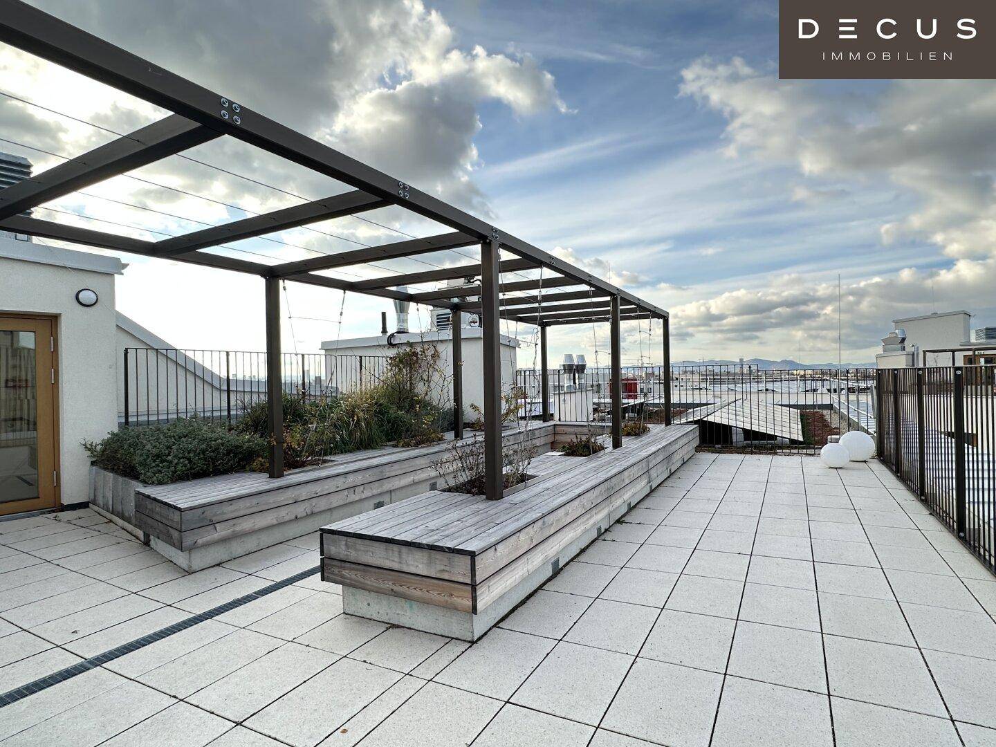 Geräumige Dachterrasse mit Holzbank-Pflanzgefäßen, Fliesenboden und einer modernen Pergola-Struktur.