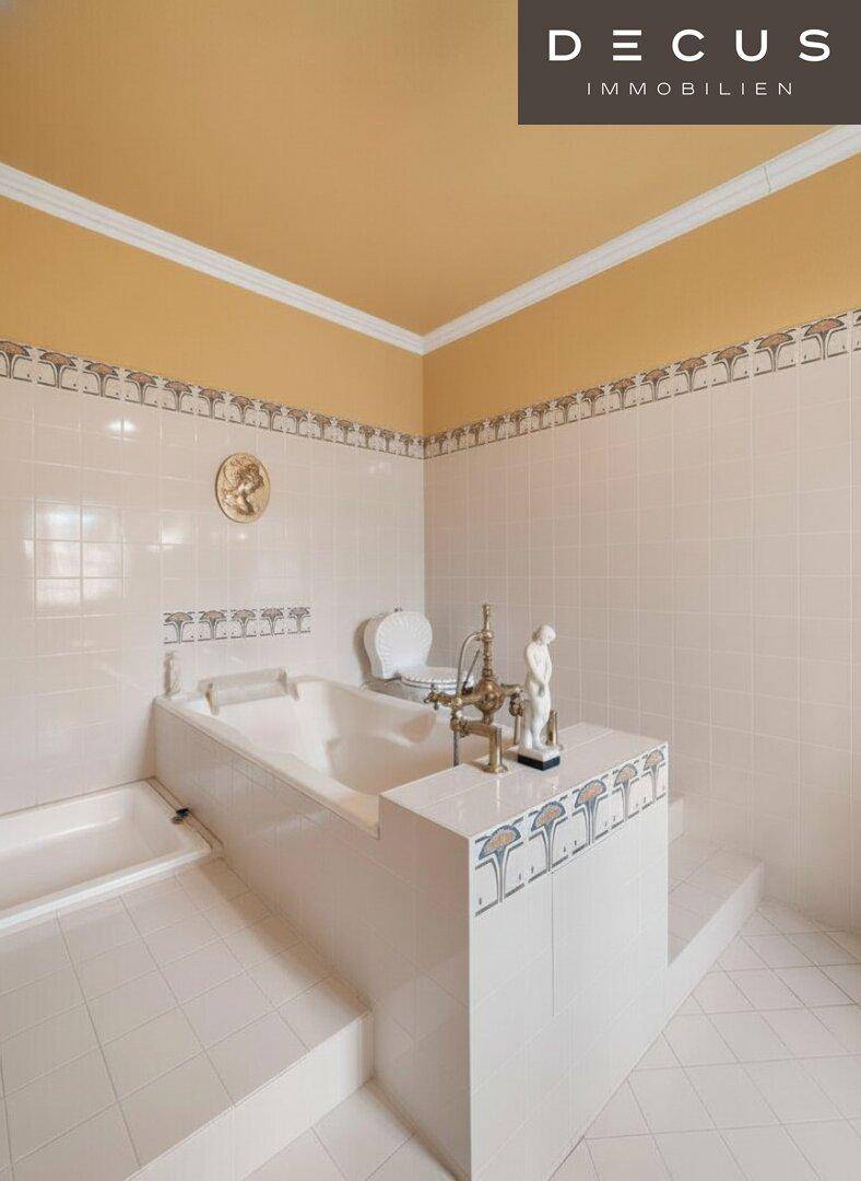 Badezimmer mit eingebauter Badewanne, gemusterten Fliesen und dekorativer Decke.