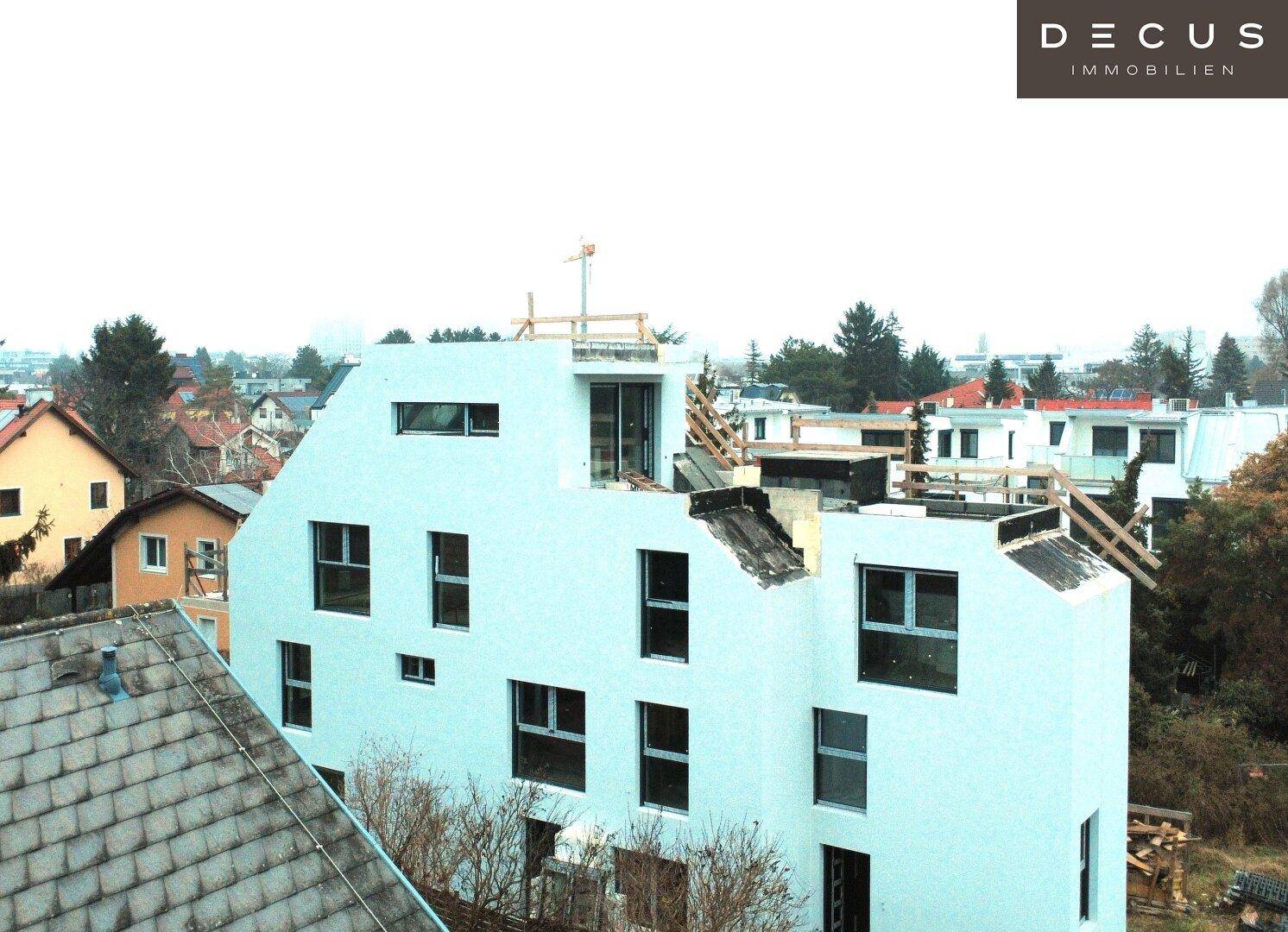 Neubau eines modernen Wohngebäudes im Rohbauzustand mit umliegender Bebauung und Dachkonstruktion.