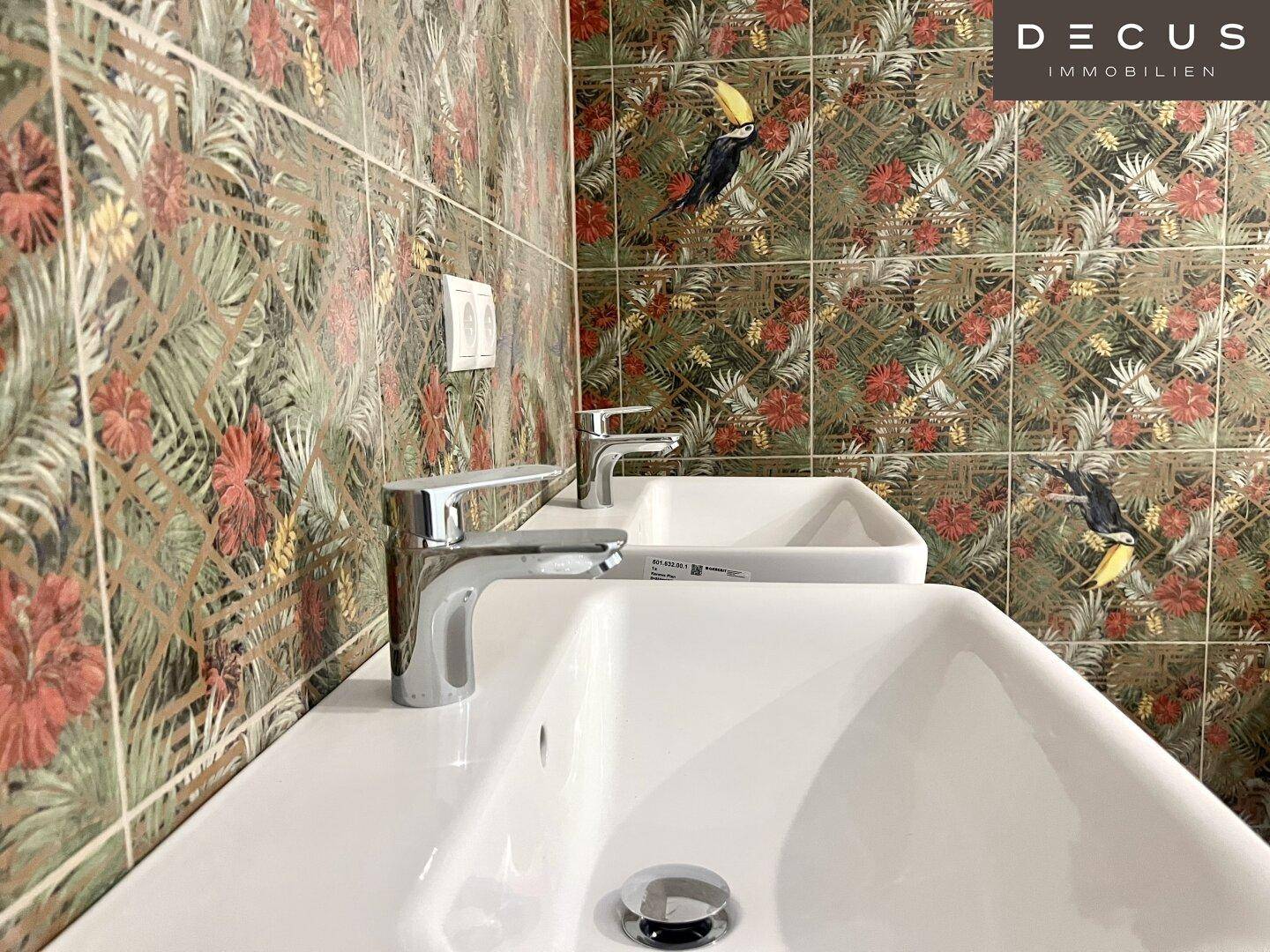 Badezimmer mit zwei Waschbecken und auffälligen, tropisch gemusterten Fliesen.