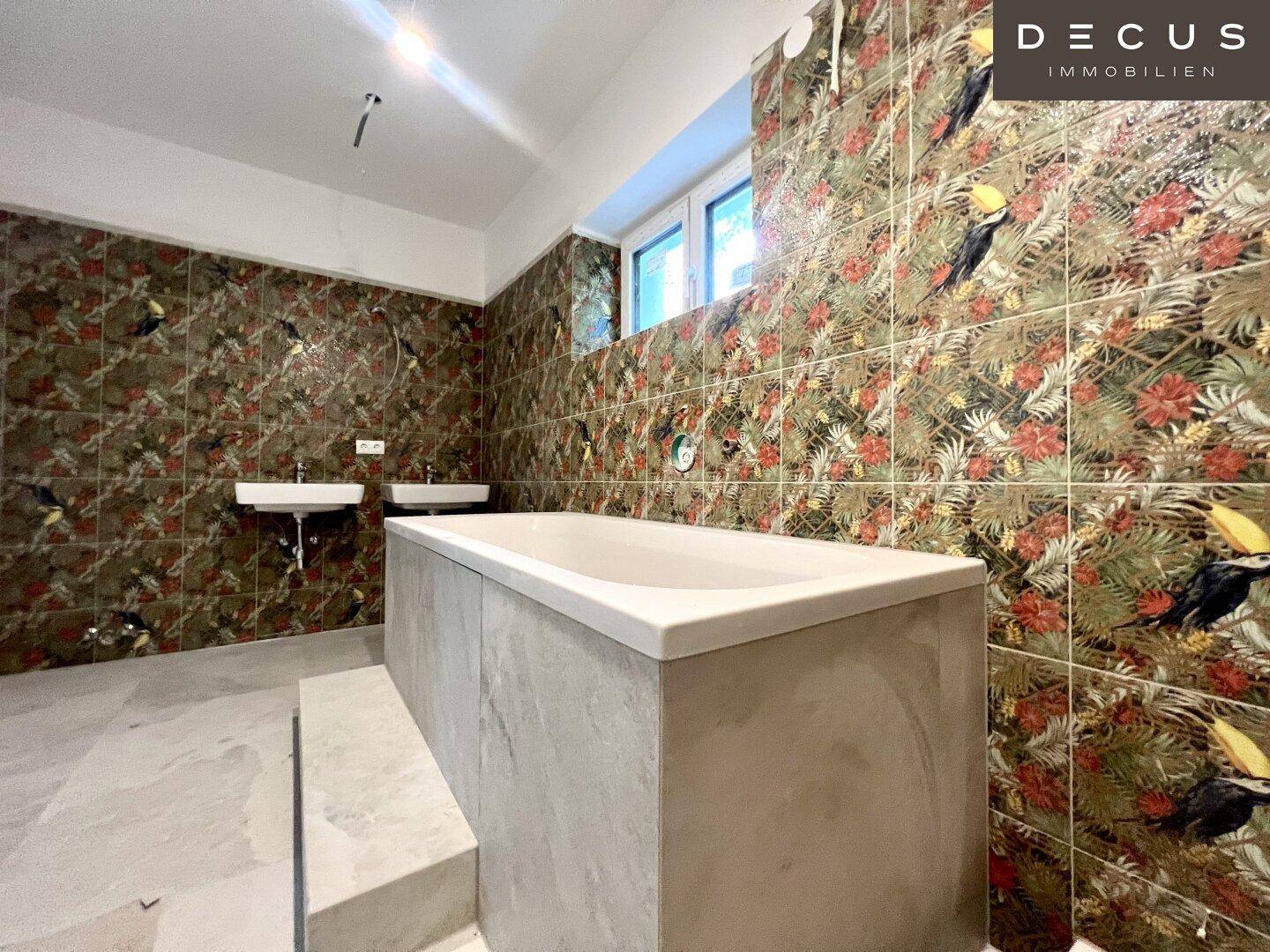 Geräumiges Badezimmer mit Badewanne und farbenfrohen, gemusterten Wandfliesen.