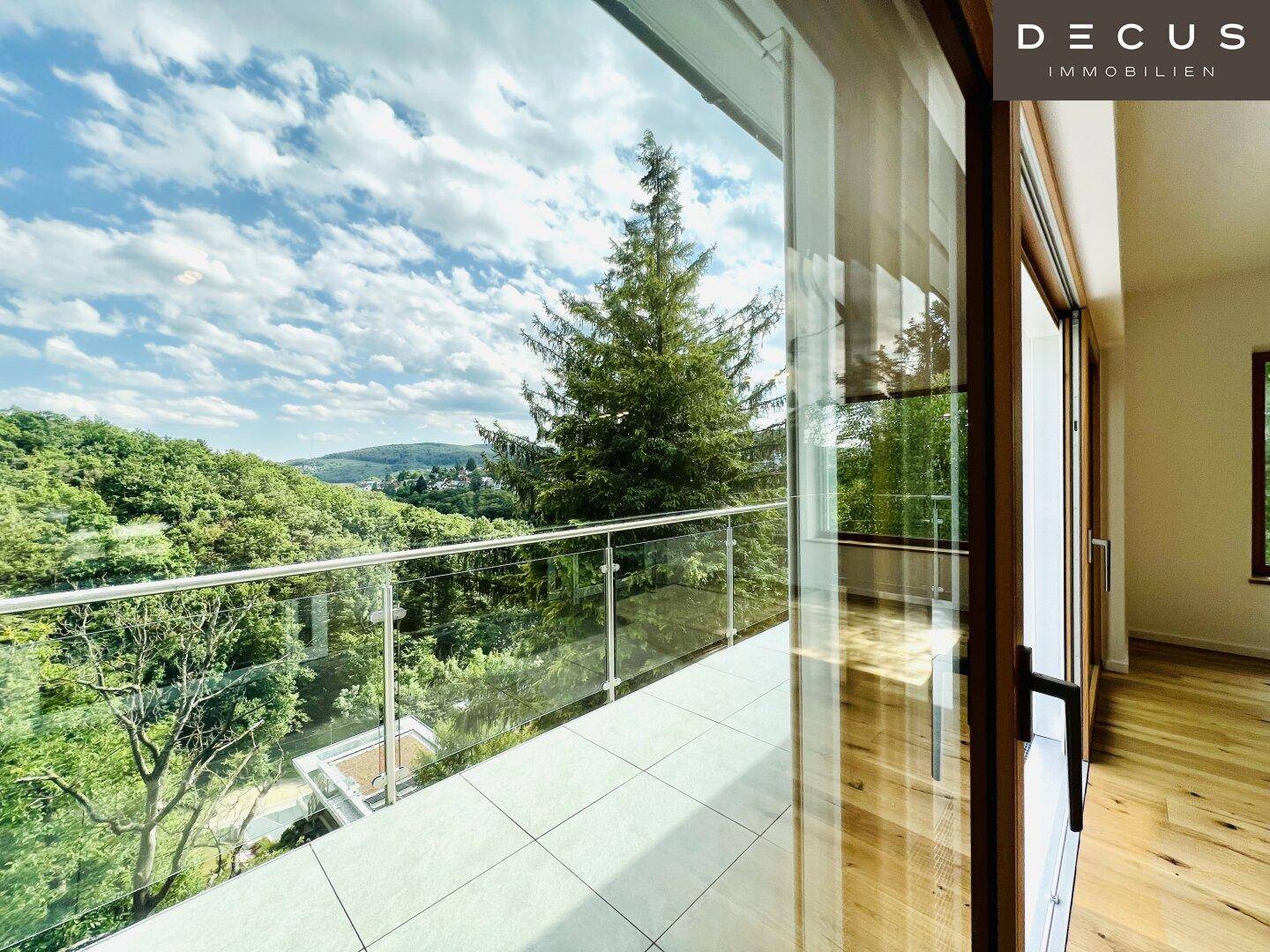 Helles Zimmer mit großen Schiebetüren und weitem Blick ins Grüne von einem Balkon.