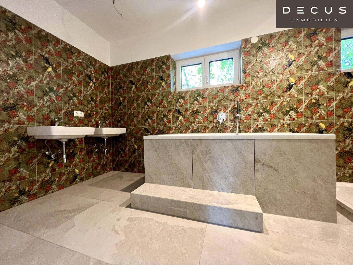 Geräumiges Badezimmer mit Badewanne und farbenfrohen, gemusterten Wandfliesen.