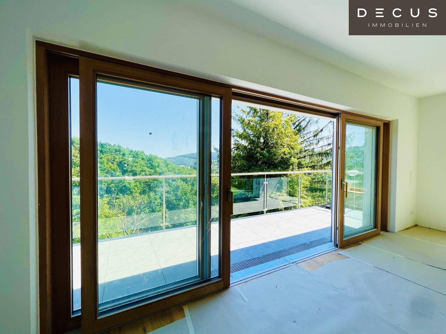 Geräumiges Zimmer mit großen Glasschiebetüren, die auf einen Balkon mit schöner Aussicht führen.