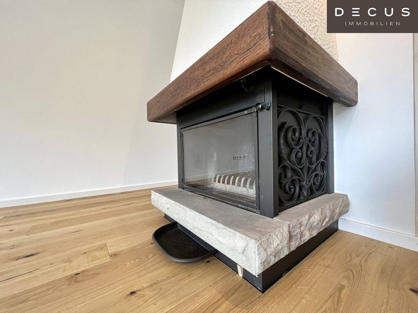 Gemütlicher Kamin mit Holzverkleidung und Steinsockel in einem hellen Raum.