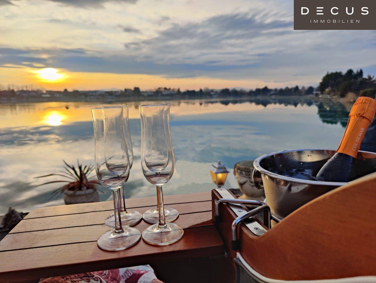 Romantischer Sonnenuntergang am See mit Sekt und Gläsern auf einem privaten Holzsteg.