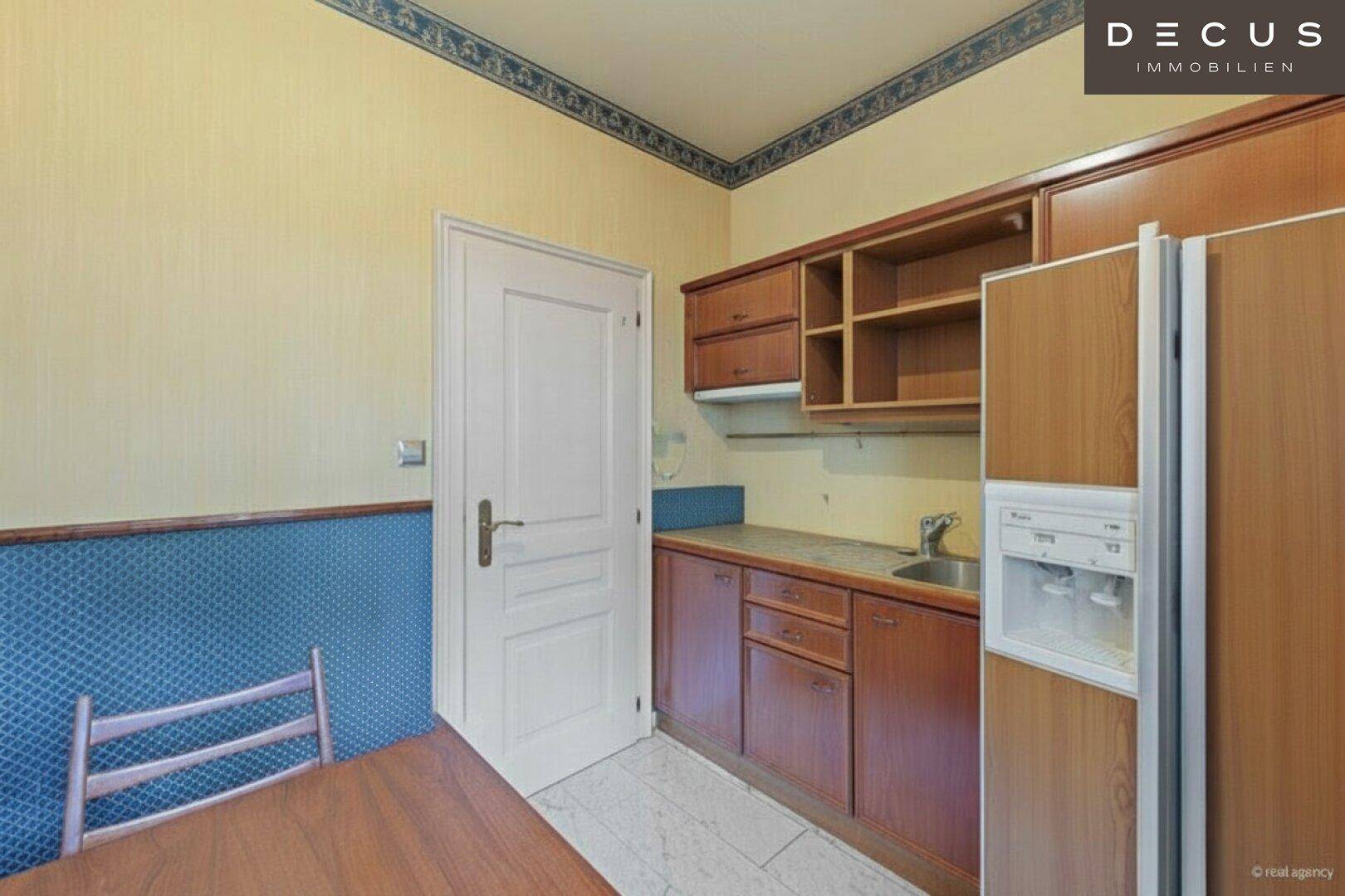 Kleine Küche oder Kochnische mit Holzschränken und einem Kühlschrank.