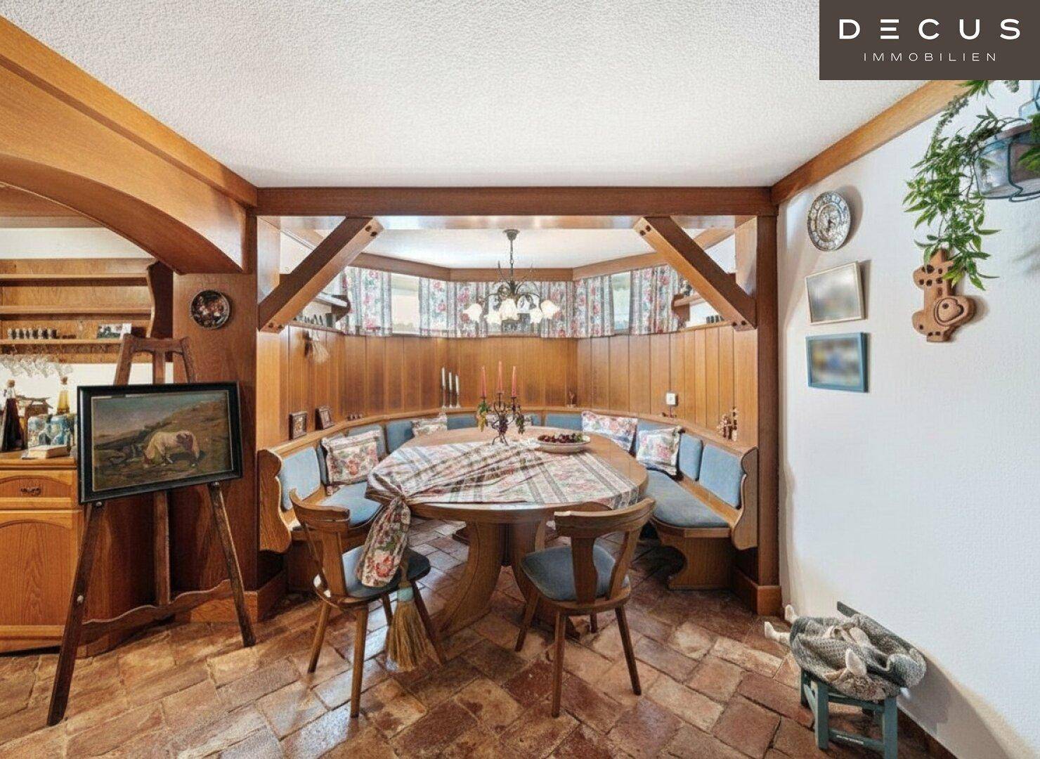 Traditioneller Essbereich mit großem Holztisch, eingebauten Bänken und sichtbaren Holzbalken.