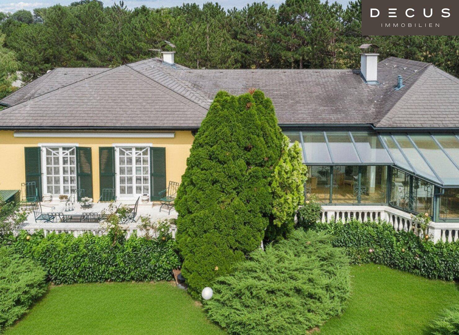 Detailansicht der Hausfassade mit Fenstern, kleiner Terrasse und einem verglasten Wintergarten.