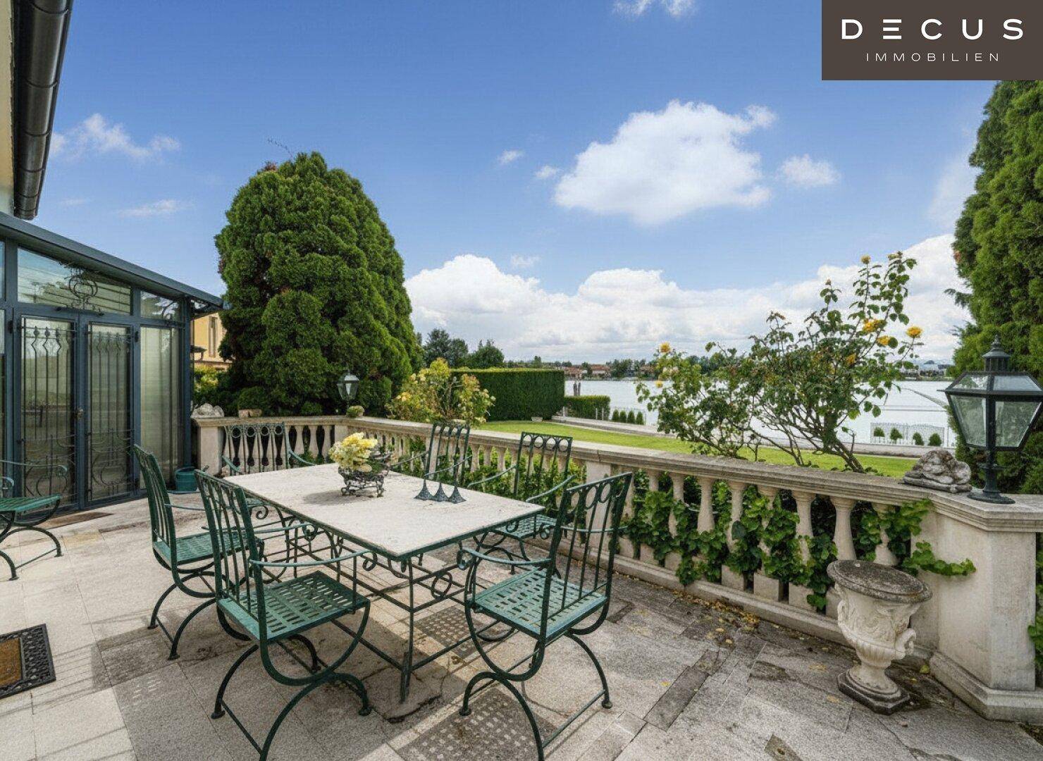 Geräumige Terrasse mit Gartenmöbeln neben dem Wintergarten und weitem Seeblick.