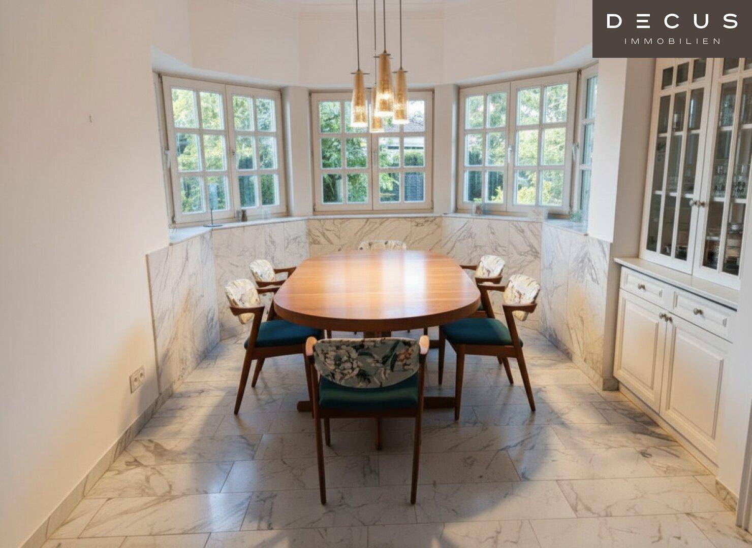 Eleganter Essbereich mit Holztisch, Stühlen und Erkerfenstern, verziert mit Marmorverkleidung.