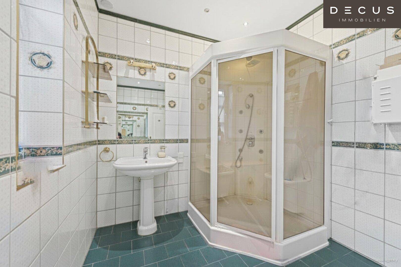 Badezimmer mit Eckduschkabine, weißen Fliesen und einem Standwaschbecken.