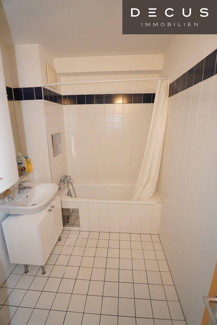 Funktionales Badezimmer mit Badewanne, Duschvorhang und weißen Fliesen.