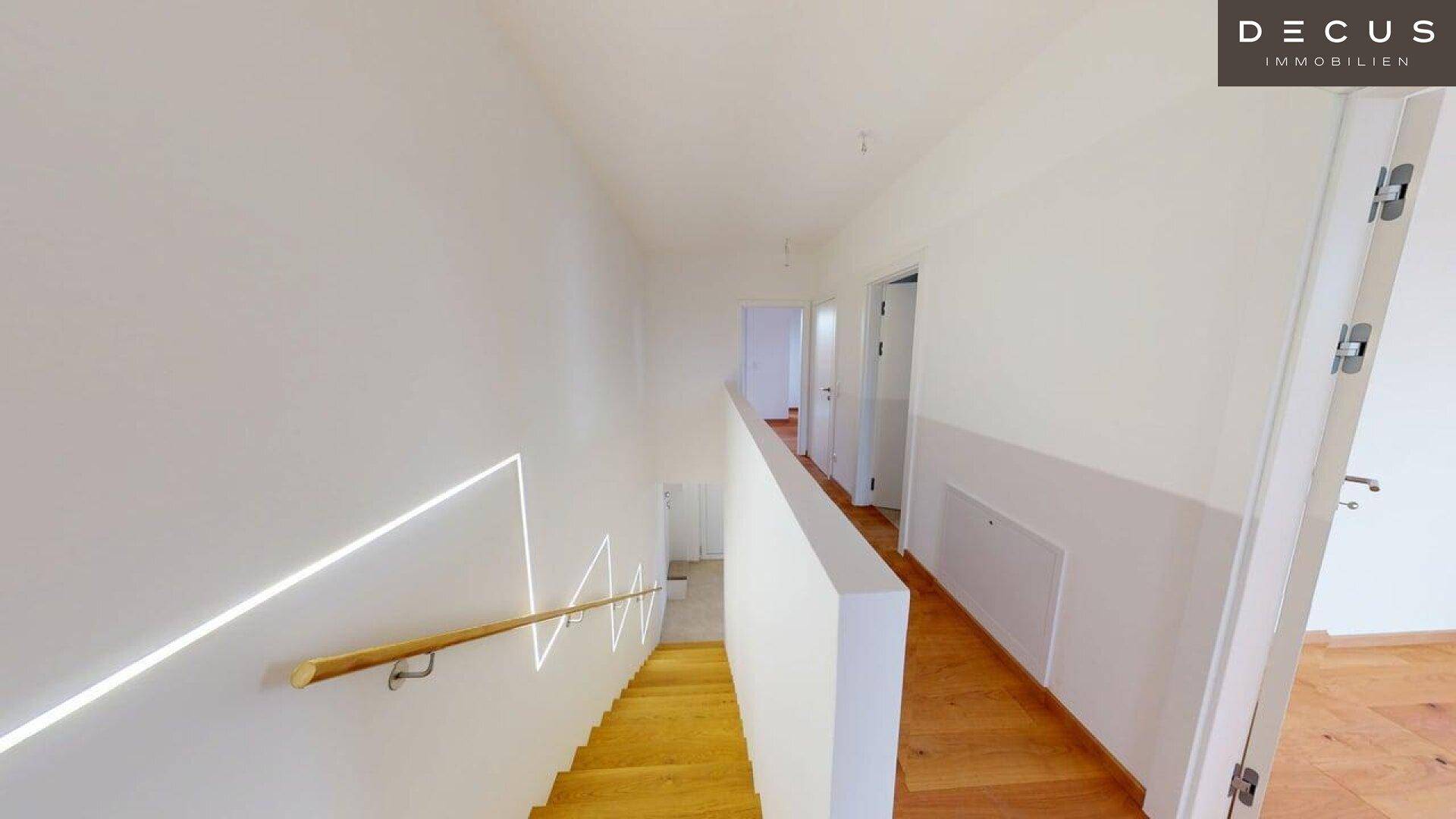 Oberer Flur mit Holzboden und Blick auf die beleuchtete Treppe.