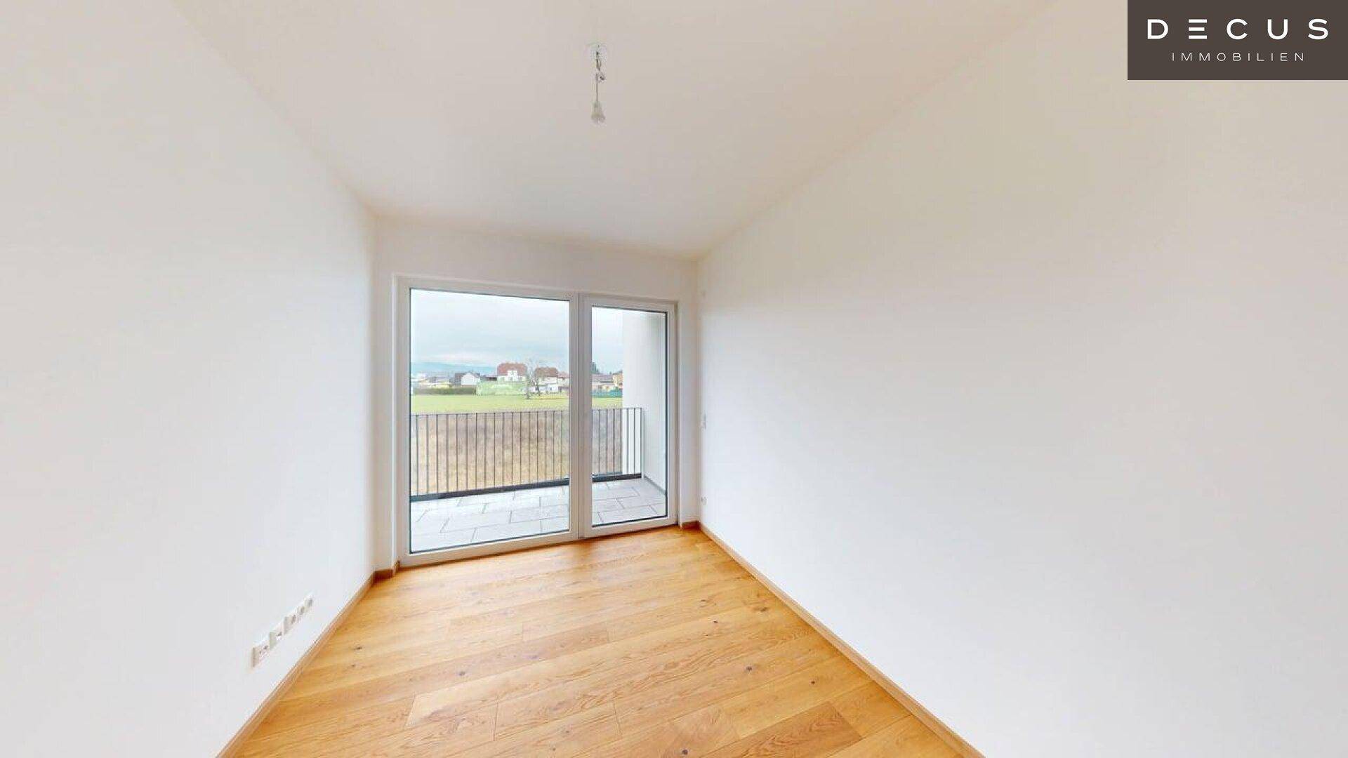 Schlafzimmer mit Holzboden und Zugang zu einem Balkon, der einen weiten Blick bietet.