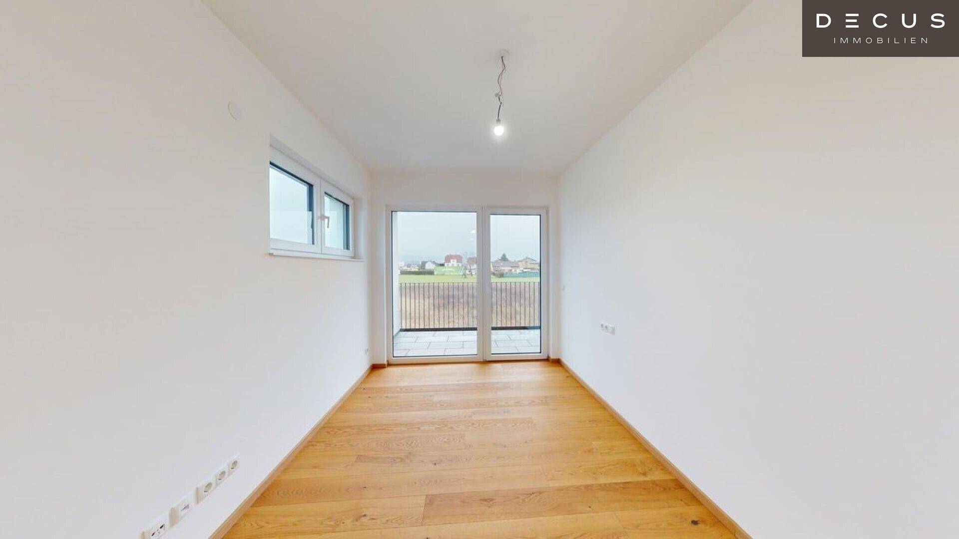 Helles Schlafzimmer mit großem Fenster und Balkontür, die viel Licht hereinlässt.