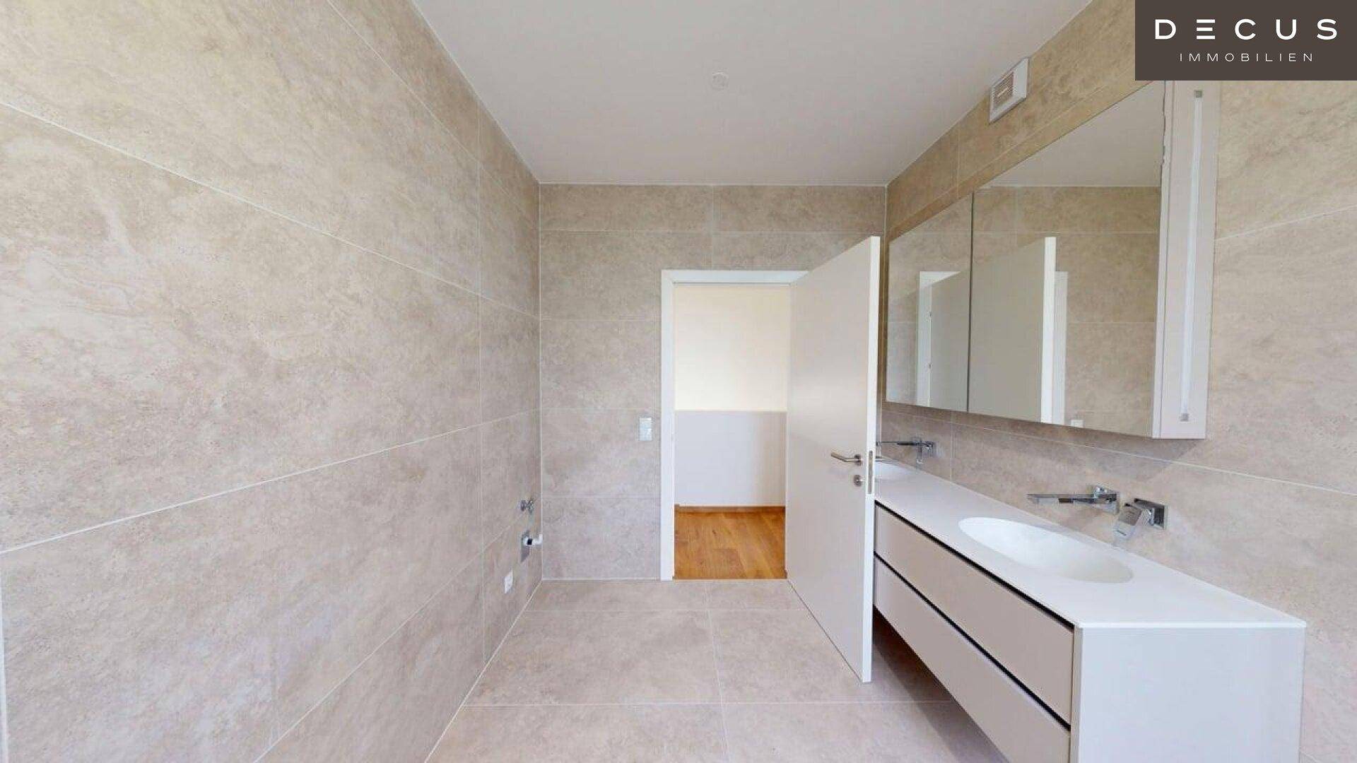 Geräumiges Badezimmer mit modernen Fliesen und einem Waschtisch mit Spiegelschrank.