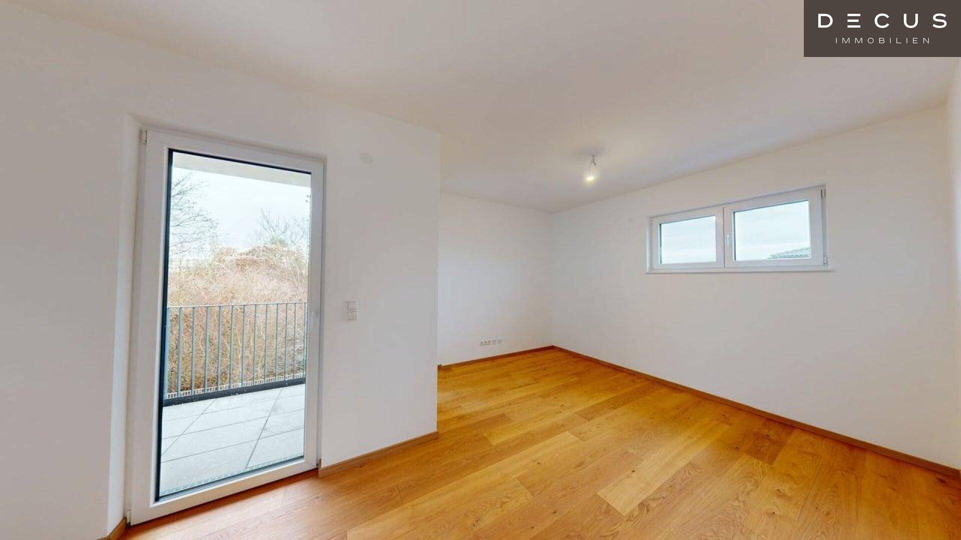 Schlafzimmer mit Holzboden und Balkontür, die Zugang zu einem Außenbereich bietet.