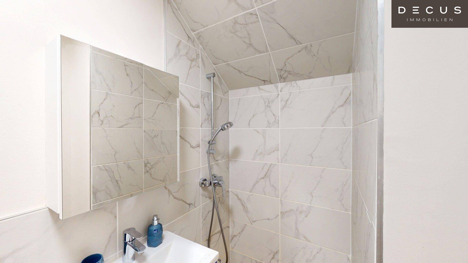 Moderne Dusche mit Marmorfliesen und integriertem Spiegel.