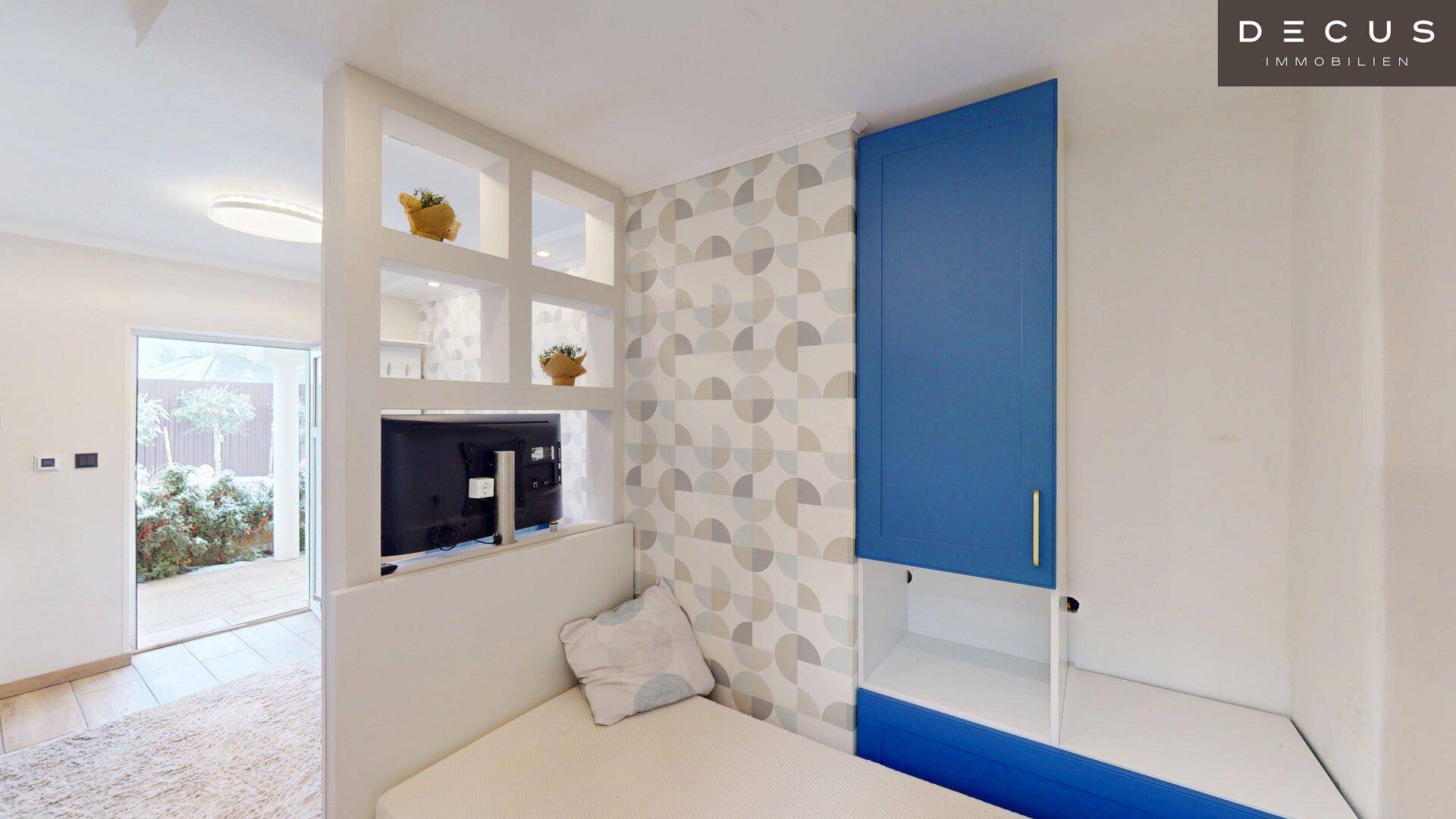 Kompaktes Schlafzimmer mit Bett, blauen Schränken und dekorativer Tapete.
